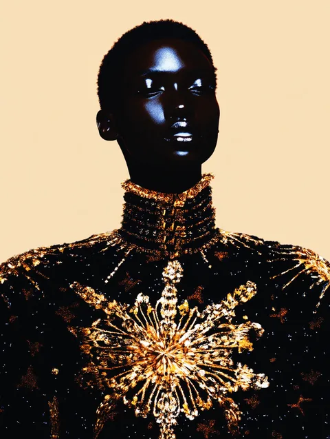 Ein glänzend schwarzes Gesicht über einem goldenen, sternförmigen Brustschmuck.