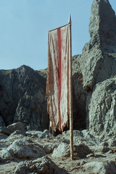 Ein schmales, verwittertes Stoffbanner zwischen dunklen Felsen.