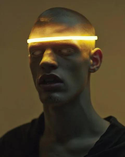 Ein kahles Gesicht mit einer waagerechten gelben Lichtlinie auf Augenhöhe.